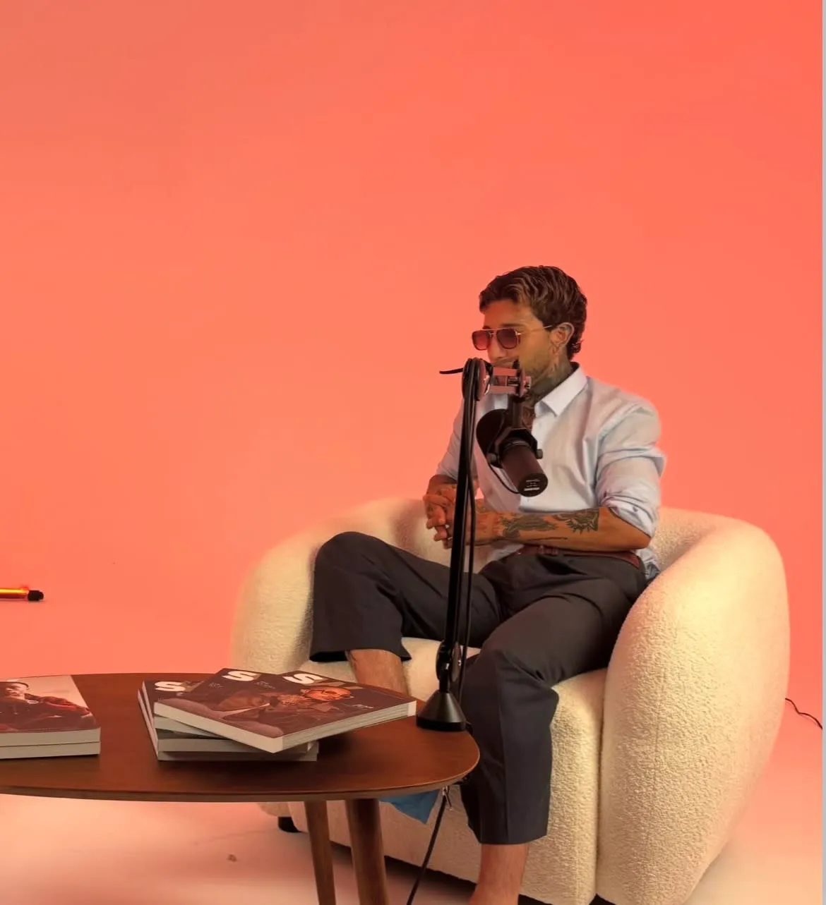 Grabación de podcast en el estudio: invitado con micrófono sobre fondo coral